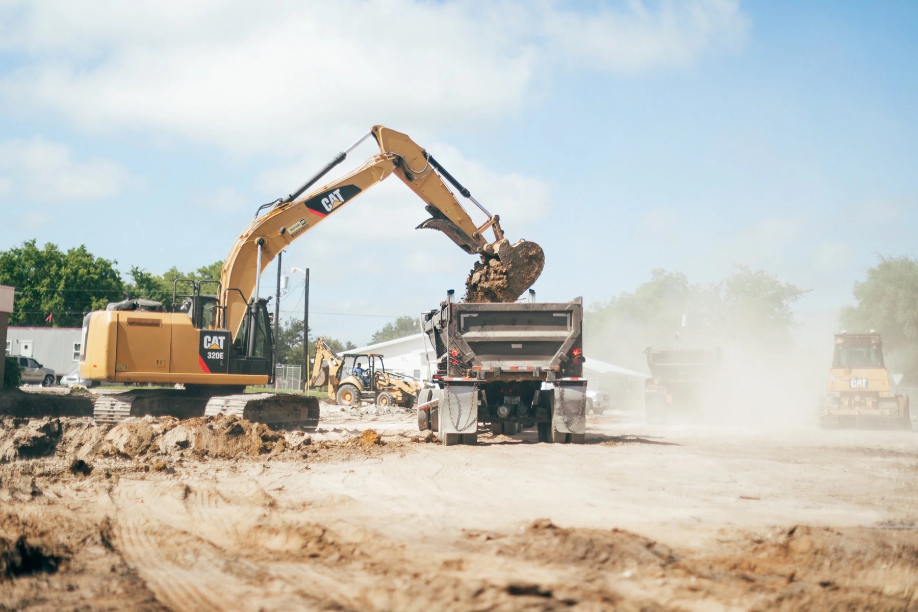 An excavator loading material into a dump truck on a job site